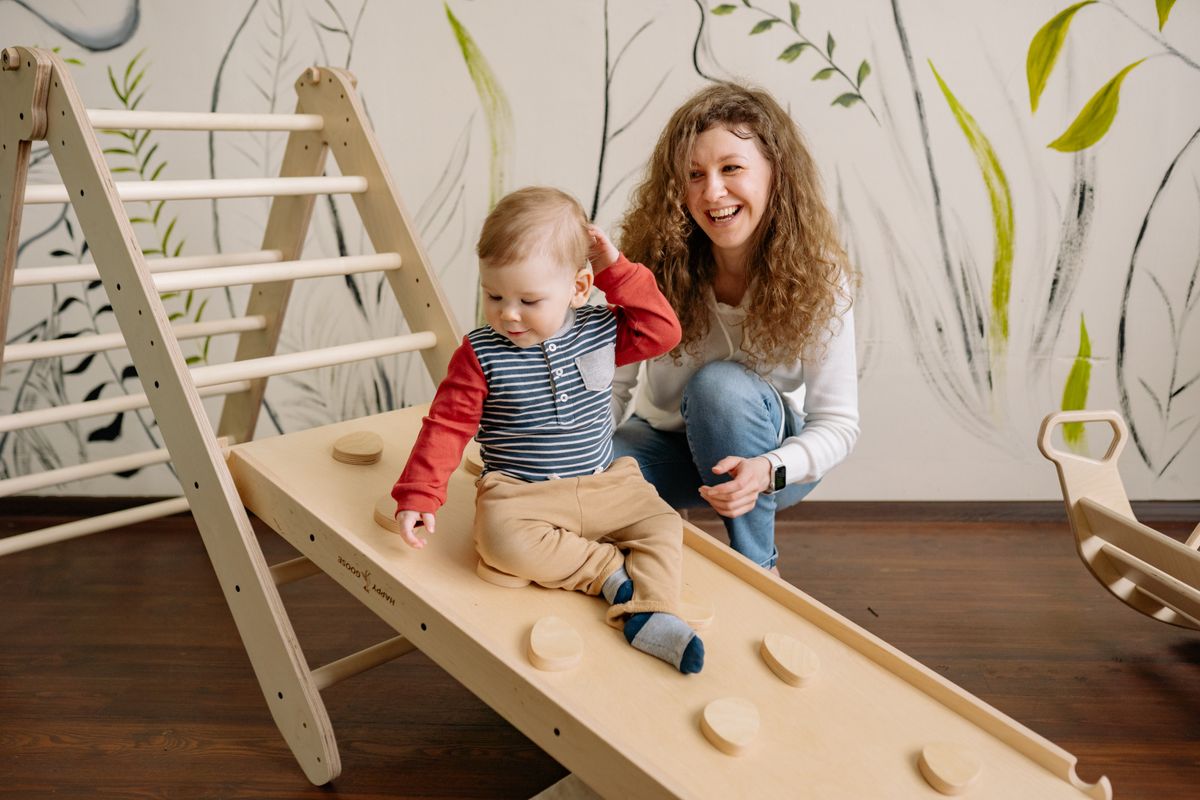 A joyful interaction between a mother and her child on a wooden playground indoors, nurturing happiness. A joyful interaction between a mother and her child on a wooden playground indoors, nurturing happiness.