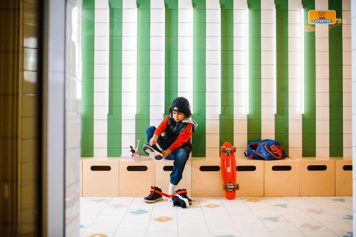 Photo by Anastasia Shuraeva on Pexels Young child in a locker room tying shoes surrounded by skateboard and backpack, ready for fun and activity. - Photo by Anastasia Shuraeva on Pexels