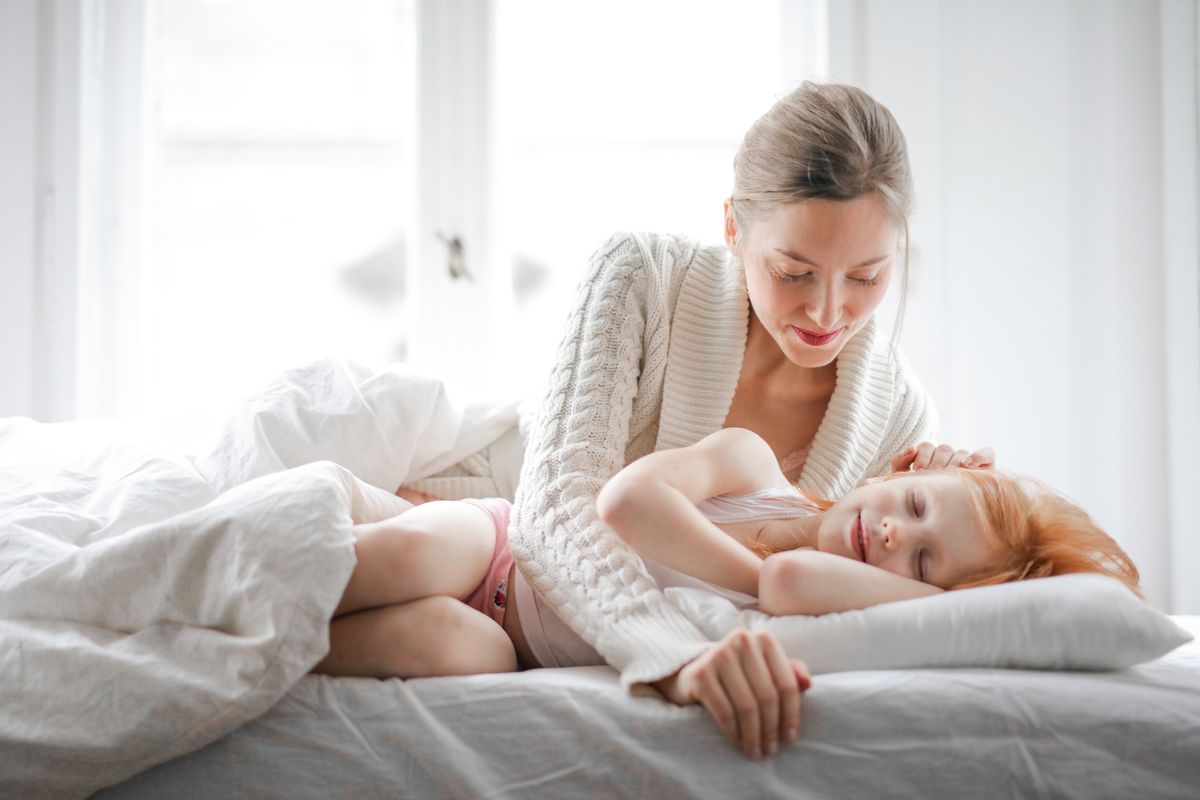 Photo by Andrea Piacquadio on Pexels Low angle of joyful young woman in casual clothes lying and caressing small girl sleeping in soft bed in light modern bedroom at home in daytime - Photo by Andrea Piacquadio on Pexels