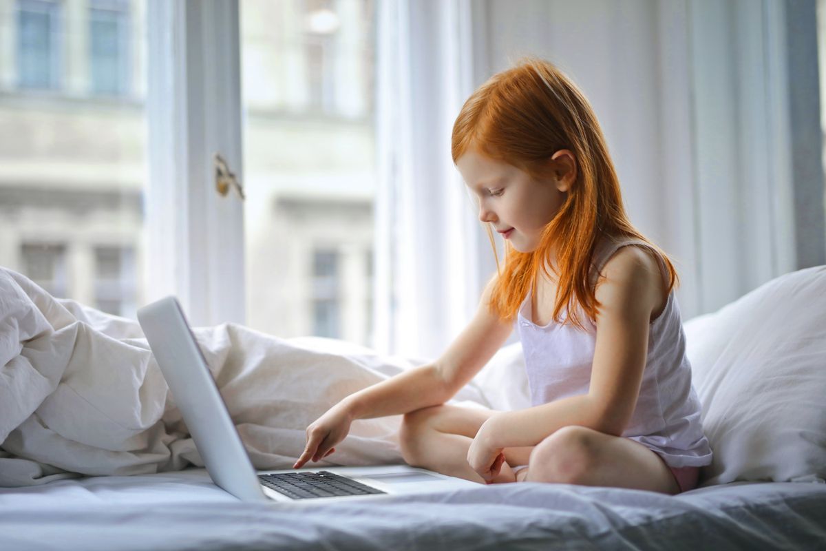 Photo by Andrea Piacquadio on Pexels Redheaded girl sits on bed using laptop in a sunlit bedroom, enjoying leisure time. - Photo by Andrea Piacquadio on Pexels
