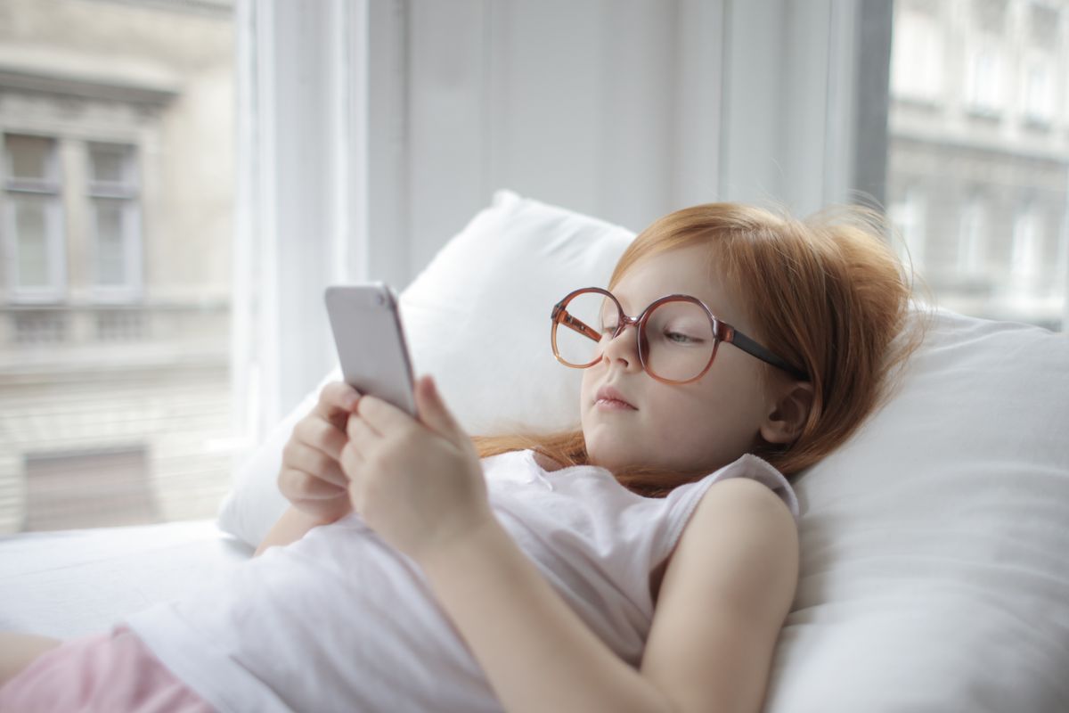 Photo by Andrea Piacquadio on Pexels Girl relaxing indoors with a smartphone, showcasing modern childhood leisure. - Photo by Andrea Piacquadio on Pexels