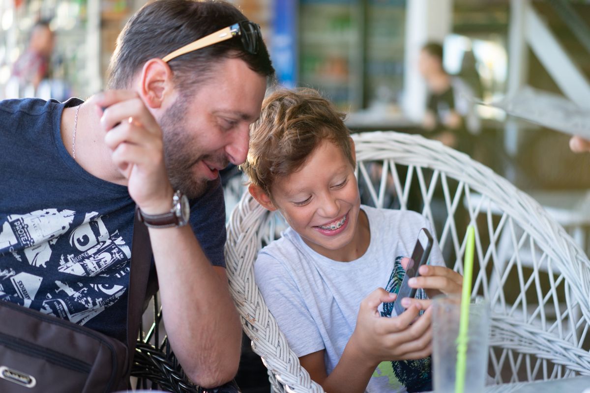 Photo by Atlantic Ambience on Pexels Father and son bonding over a smartphone, sharing a joyful moment in a cozy cafe. - Photo by Atlantic Ambience on Pexels