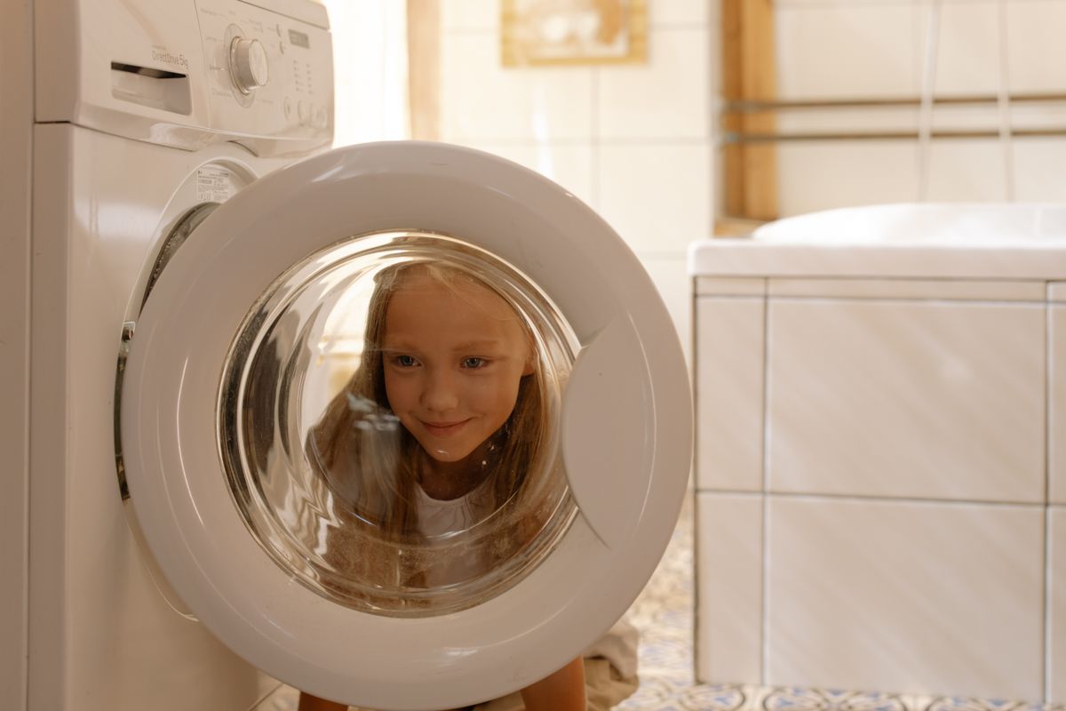 Photo by cottonbro studio on Pexels Ein junges Mädchen blickt neugierig in die Waschmaschinentür in einem hellen, modernen Badezimmer. - Foto von Cottonbro Studio auf Pexels