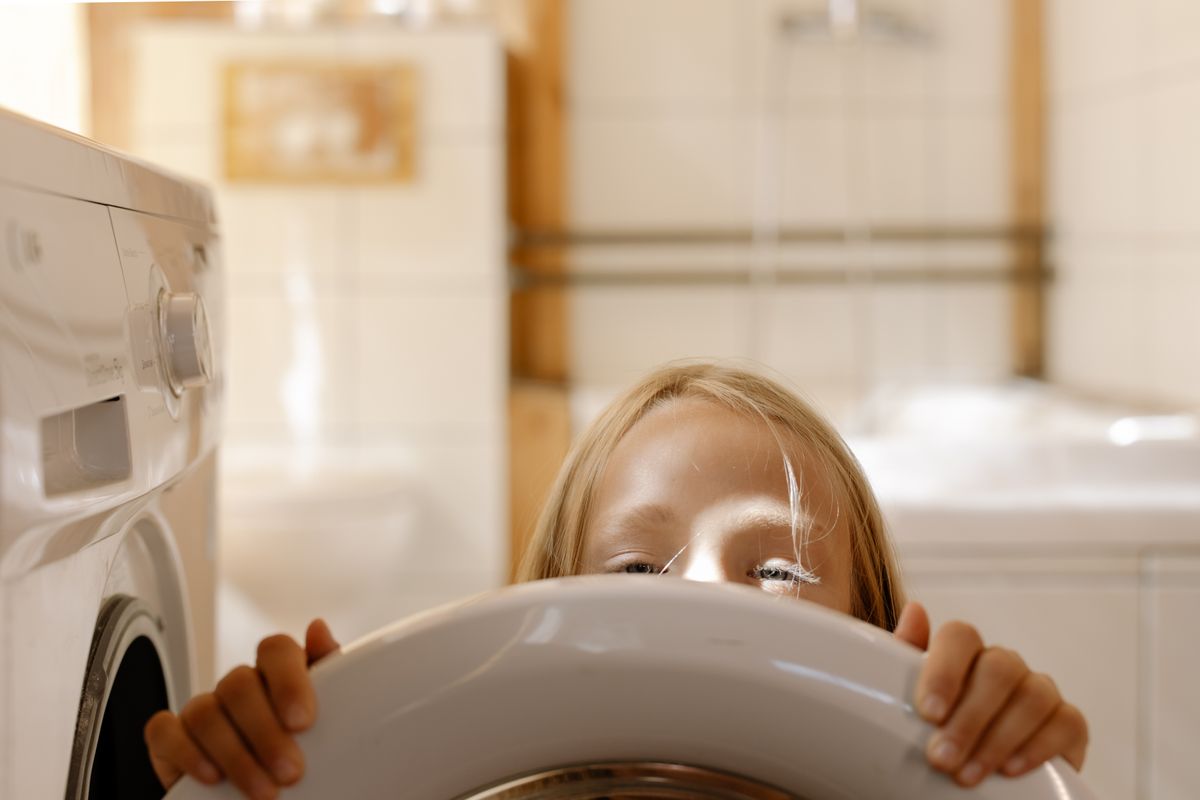 Photo by cottonbro studio on Pexels Junges Mädchen schaut aus der Waschmaschine und hilft drinnen bei der Wäsche. - Foto von Cottonbro Studio auf Pexels