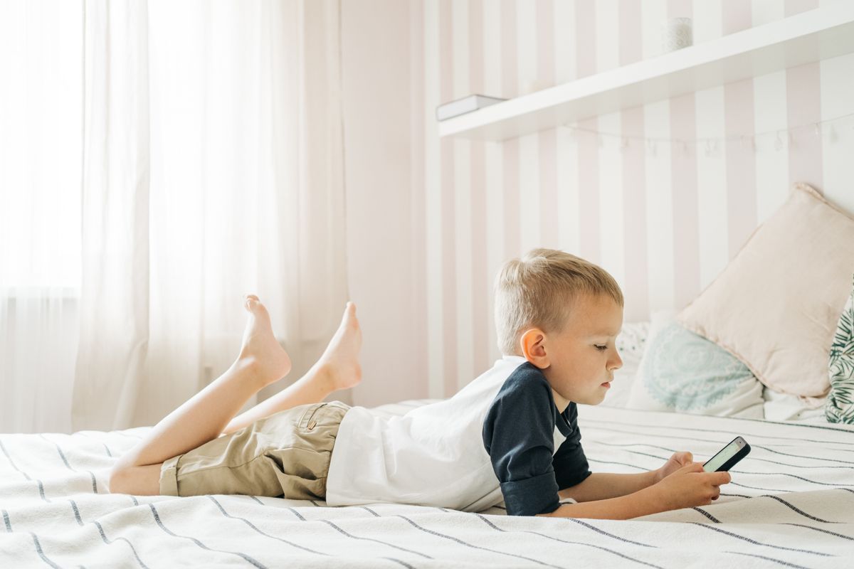 Photo by Ivan S on Pexels Kleiner Junge liegt mit Smartphone in einem hellen Raum im Bett und genießt seine Freizeit. - Foto von Ivan S auf Pexels