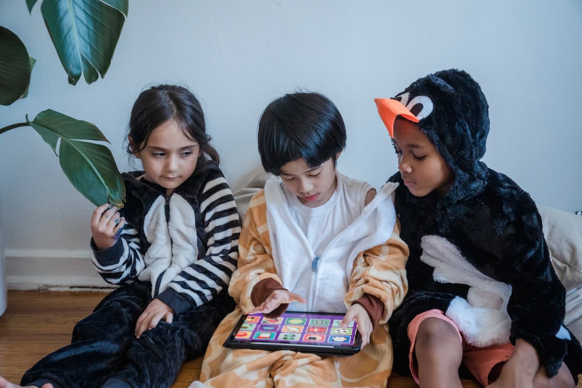 Photo by Liliana Drew on Pexels Kinder in Tier-Strampler spielen drinnen auf einem Tablet und genießen ihre Freizeit. - Foto von Liliana Drew auf Pexels