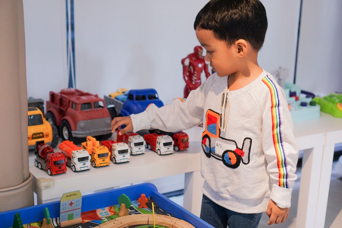 Photo by pipop kunachon on Pexels A young boy playing indoors with colorful toy trucks on a table, focused and imaginative. - Photo by pipop kunachon on Pexels