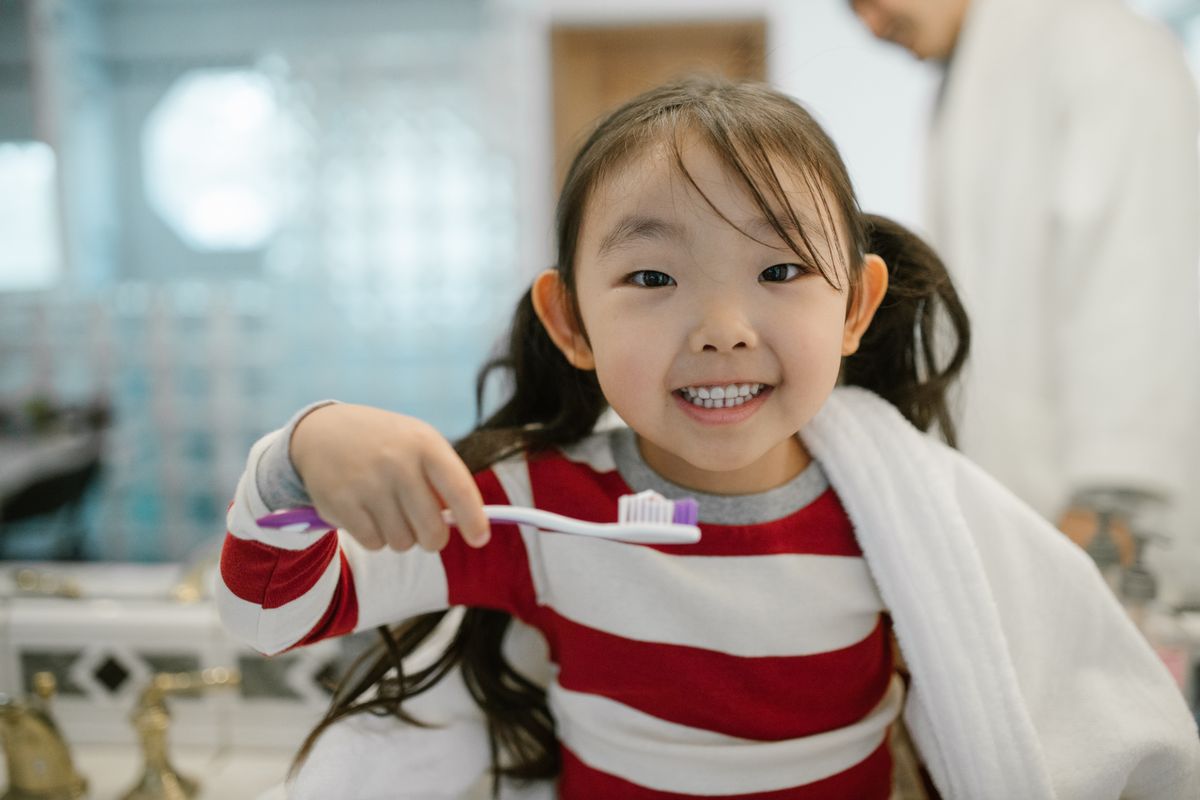 Photo by RDNE Stock project on Pexels Ein lächelndes junges Mädchen in einem Badezimmer hält eine Zahnbürste in der Hand und fördert die Zahnhygiene. - Foto von RDNE Stock-Projekt auf Pexels