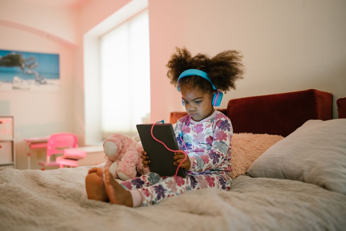 Photo by RDNE Stock project on Pexels Ein junges Mädchen im Schlafanzug sitzt mit Kopfhörern auf dem Bett und bedient ein Tablet. Gemütliches Zuhause. - Foto von RDNE Stock-Projekt auf Pexels