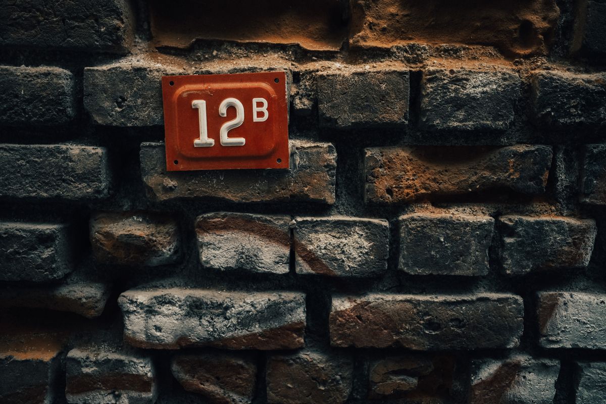 Photo by Sami Aksu on Pexels Close-up of a vintage red number plate '12B' mounted on a rustic brick wall. - Photo by Sami Aksu on Pexels
