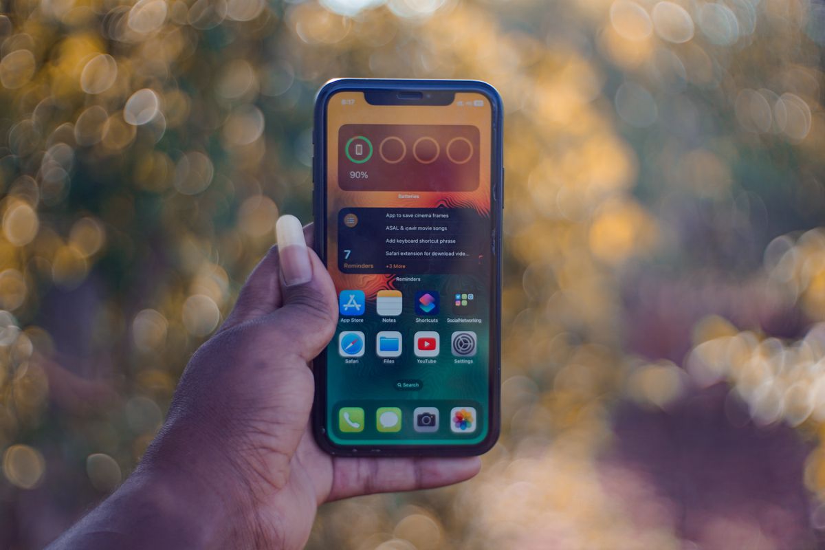 Photo by Soundarapandian MS on Pexels Eine Hand, die ein Smartphone hält und Apps auf dem Startbildschirm zeigt, im Freien mit Bokeh-Hintergrund. - Foto von Soundarapandian MS auf Pexels