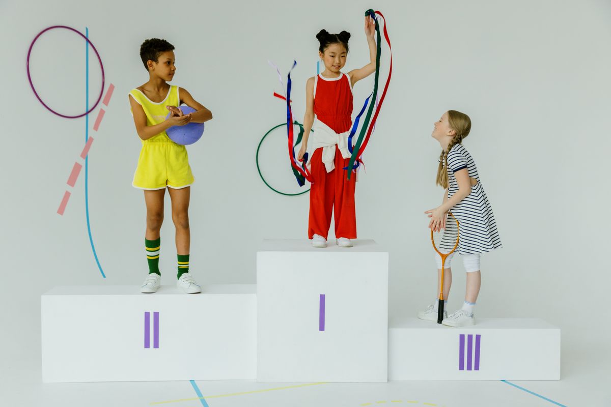 Three happy children celebrating on a gymnastics podium with equipment. Three happy children celebrating on a gymnastics podium with equipment.
