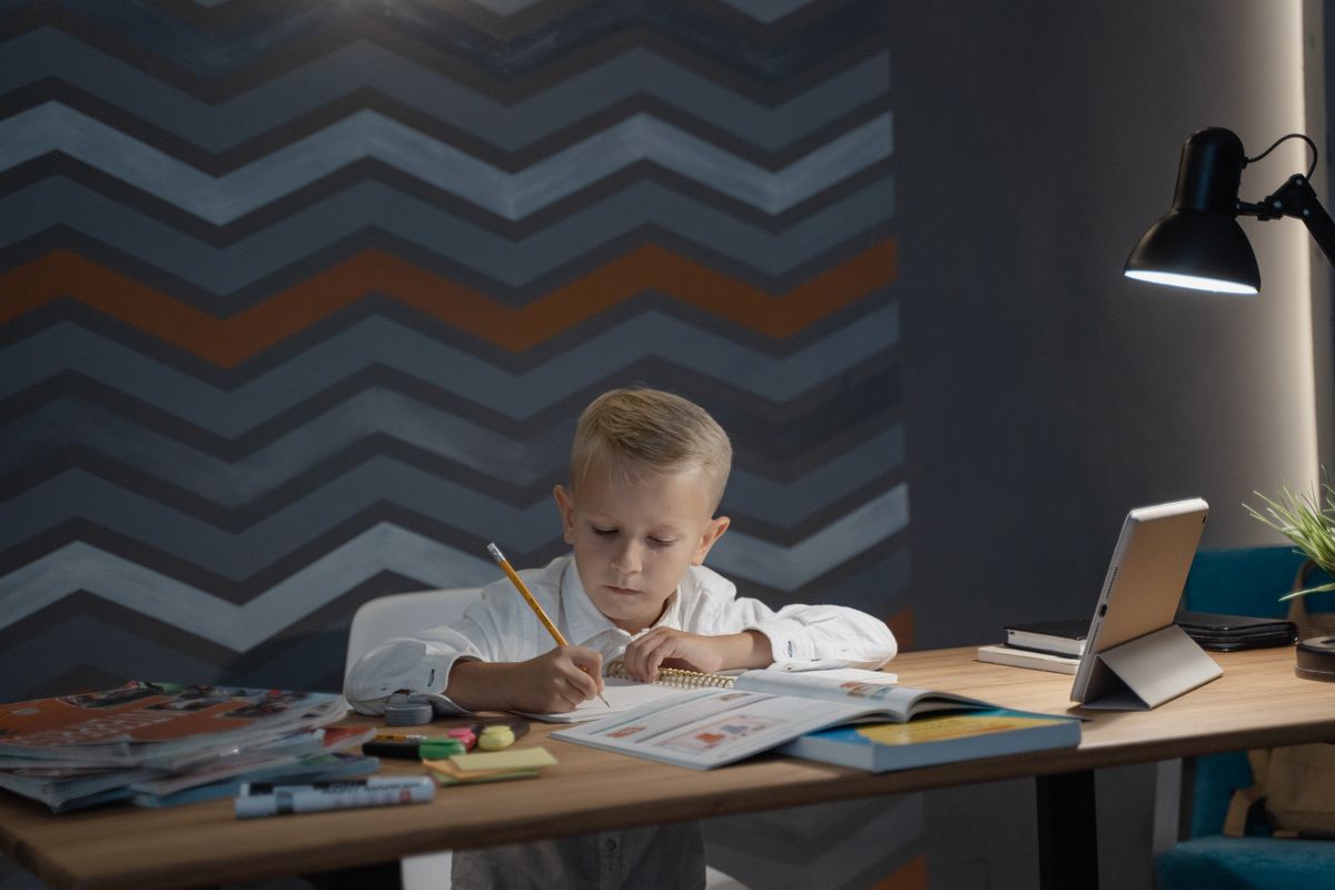 Photo by Tima Miroshnichenko on Pexels Ein Kind konzentriert sich an einem Schreibtisch mit Tablet und Lampe auf seine Hausaufgaben und fördert so die Bildung zu Hause. - Foto von Tima Miroshnichenko auf Pexels