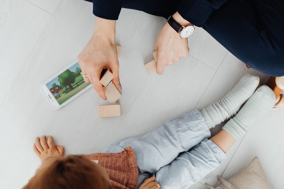 Photo by www.kaboompics.com on Pexels A mother and child playing with wooden blocks and a smartphone on the floor. - Photo by www.kaboompics.com on Pexels