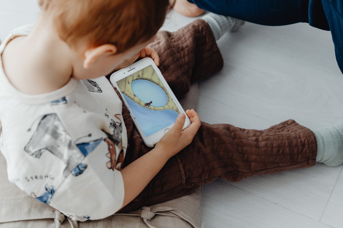 A young child using a phone indoors - Photo by www.kaboompics.com on Pexels