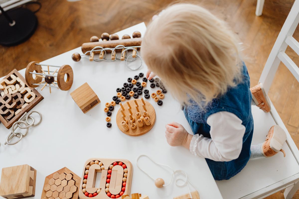 Photo by www.kaboompics.com on Pexels Ein Kind, das an einem Tisch mit Holzspielzeug lernt, perfekt für frühe Bildungsthemen. - Foto von www.kaboompics.com auf Pexels